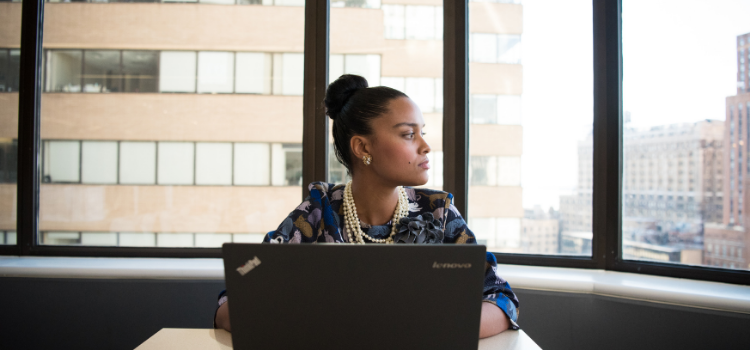 Woman looking out of window on a laptop