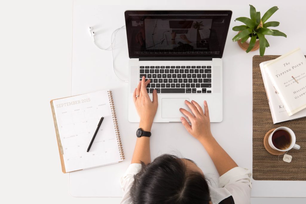 Lady using a laptop and notebook on desk