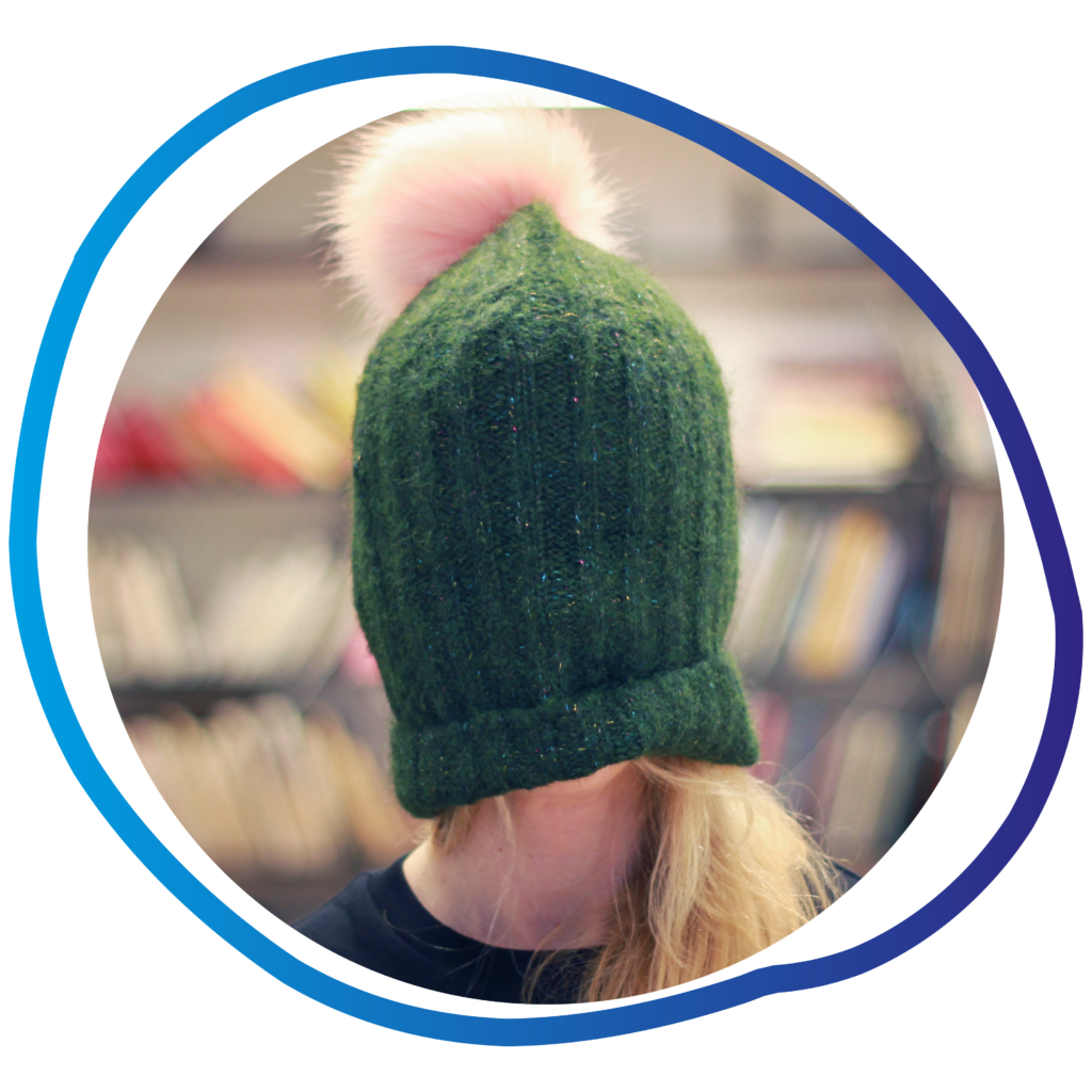 a person wearing a green hat with a pink pom